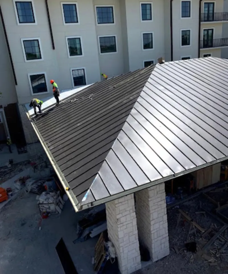 Crew installing standing seam metal roof panels on a commercial project in Gonzales